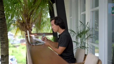 Asian man write notebook outside cafe. Freelancer person online internet work. Stock Footage 235685880