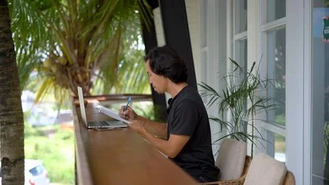 Asian man write notebook outside cafe. Freelancer person online internet work. Foto stock