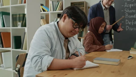 Asian Man Writing in Notebook during Diverse Migrant Education Class Stock Footage 337482837
