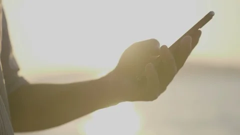 Asian man's hand? are using a smartphone at the seaside at sunset. Stock Footage 100923928