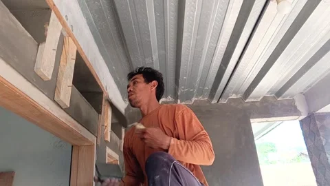 Asian mason skillfully applying wet cement to a wall above a door frame. Vídeo Stock 335018954