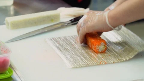 Asian master cooking orange rolls. A man make sushi on a mat of bamboo or makisu Stock Footage 119978962