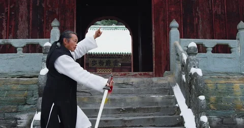 Asian master, demonstrates Tai chi martial arts sword combat in Wudang mountain Stock Footage 201096929