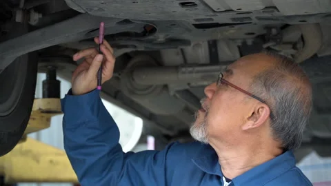 Asian mechanic senior man  checking  brake ,tyre, undercarriage of a car in w Stock Footage 147368896