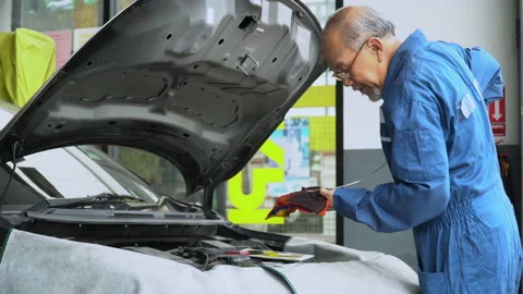 Asian mechanic senior man  checking oil level and wipes the oil dipstick of a Stock Footage 147369592