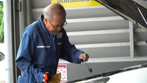 Asian mechanic senior man  checking oil level and wipes the oil dipstick of a Stock Footage 147369677