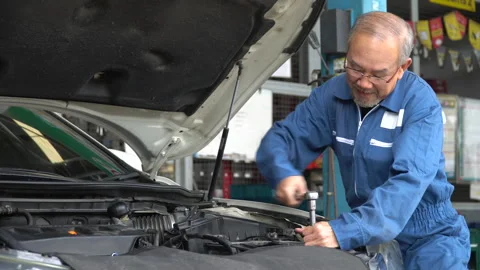 Asian mechanic senior man using socket spanner wrench repairing a car in work Stock Footage 147369235