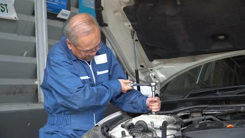 Asian mechanic senior man using socket spanner wrench repairing a car in work Stock Footage 147369521