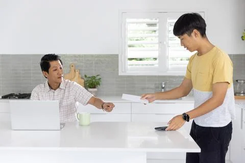 Asian men exchanging white envelope while one using laptop and placing Stock Photos