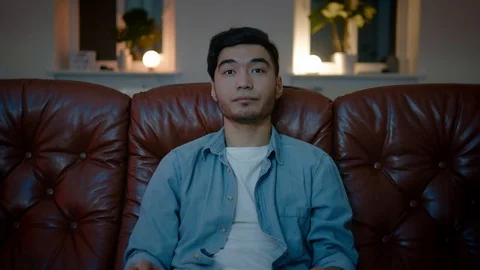 Asian men get sleepy while watching TV in cozy home at night. 스톡 동영상 105748602