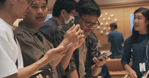 Asian men shoppers test new iPhone 17 phones inside Apple store. Handling demo  Stock Footage 322051899