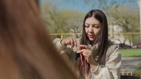 Asian mentor teaching knitting during park chat, midshot showing instructor Stock Footage 326217176