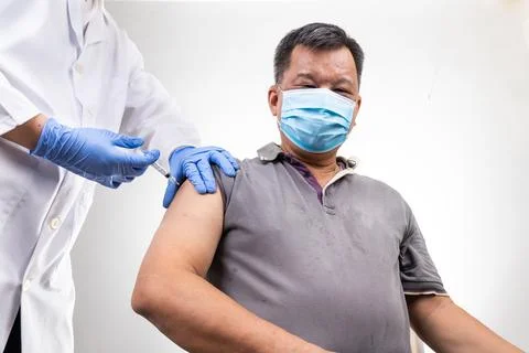 Asian middle age man receiving Covid-19 vaccine injection onto the arm Stock Photos