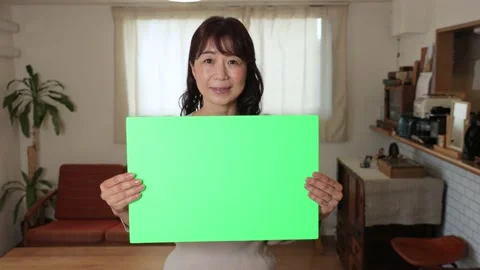 Asian middle aged lady holding green board for chromakey edit.25P. Stock Footage 221097261