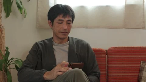 Asian middle aged man checking his smartphone at home. 25P. Stock Footage 224898409