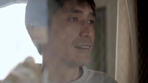 Asian middle aged man looks out of the window with smile. Stock Footage 224906400