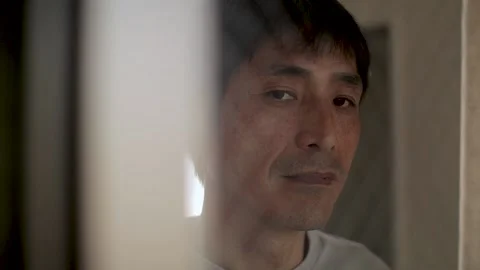 Asian middle aged man looks at the camera through the window. Unsatisfied. Stock Footage 224906582