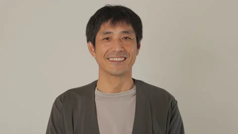 Asian middle aged man smiles at the camera. White background. 25P. Stock Footage 224899466