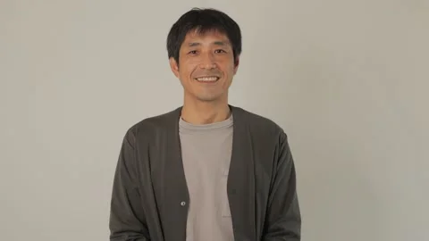 Asian middle aged man smiles at the camera. White background. 25P. Stock Footage 224899527