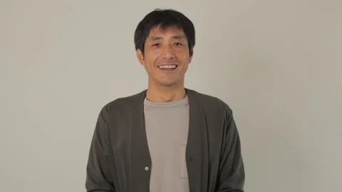 Asian middle aged man smiles at the camera. White background. Stock Footage 224903843