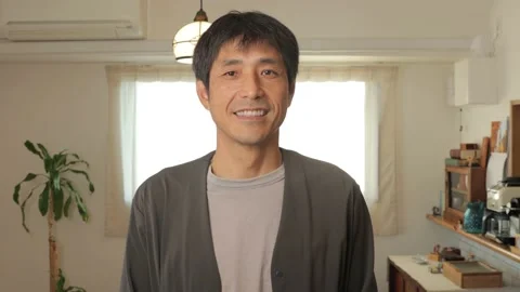 Asian middle aged man smiles at the camera in living room of apartment. Stock Footage 224904478