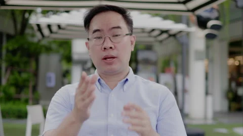 Asian middle aged man wearing glasses, headphone to video call with laptop Stock Footage 161723498