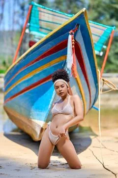 Asian model in bikini posing with old fishing boat Stock Photos