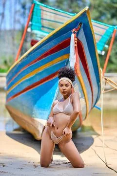 Asian model in bikini posing with old fishing boat Stock Photos