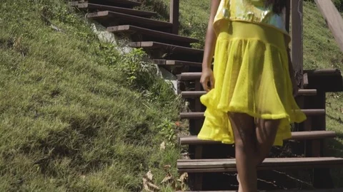 Asian model goes down the stairs in a yellow dress. Near the green grass. Stock Footage 84413003