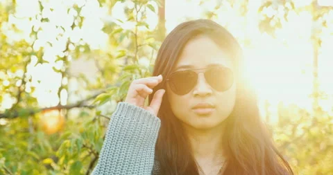 Asian model in sunglasses, looking at camera, with sunset on background. Stock Footage 130192147