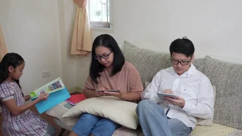 Asian mom and dad using smartphone and ignoring helping daughter Stock Footage 131511129