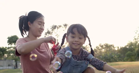 Asian mom blowing bubbles maker Stock Footage 168596569