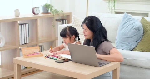 Asian mom leans close while preschool daughter smiles and draws with pencil Stock Footage 332968841
