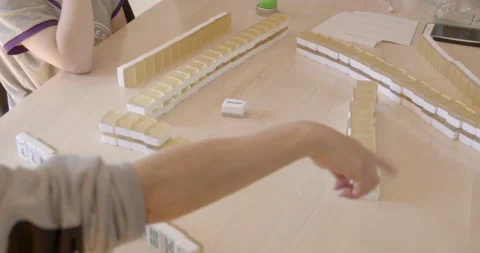 Asian mon teaching her daugthers play mahjong Stock Footage 131910591
