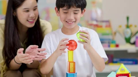 Asian Mother and Son Stacking Transparent Educational Toy Blocks Together Stock Footage 330694889