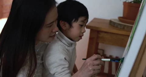 Asian mother having fun doing color paint with little son on canvas Stock Footage 149116191