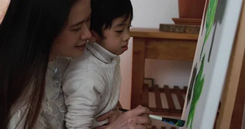 Asian mother having fun doing color paint with little son on canvas Vidéo 149116261