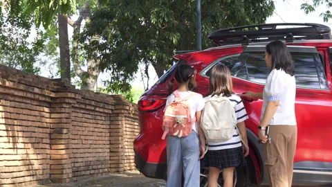 Asian mother picking up her two daughters from school by car, Back to school 库存影片 334093466