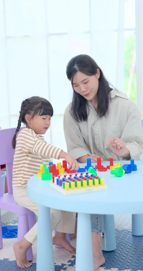 Asian mother points toy pattern for preschool daughter during guided table Stock Footage 339207288