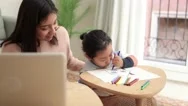 Asian Mother Taking Care Of Her Child While Working At Home - Family Lifestyle Stock Footage