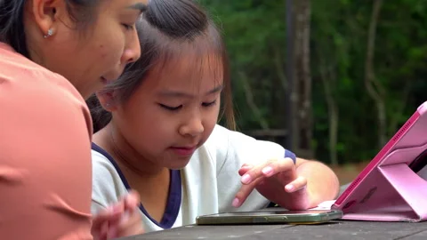 Asian mother teaching and helping her primary school daughter with homework Stockbeeldmateriaal 333663902