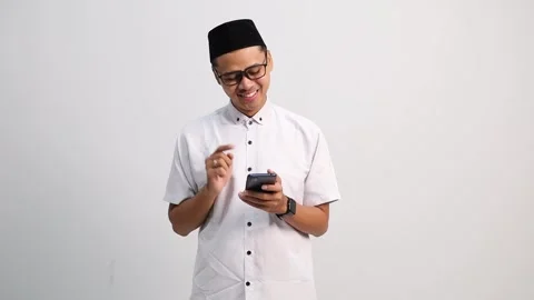 Asian Muslim man using cellphone feeling relieved and happy to get good news Stock Footage 327695434