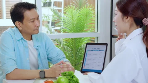 Asian nutritionist using tablet to explaining personalized meal plan with A.. Stock Footage 313068152