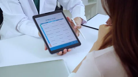 Asian nutritionist using tablet to explaining personalized meal plan with A.. Stock Footage 329456606
