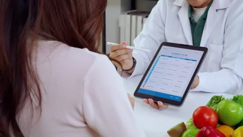 Asian nutritionist using tablet to explaining personalized meal plan with A.. Stock Footage 329913522