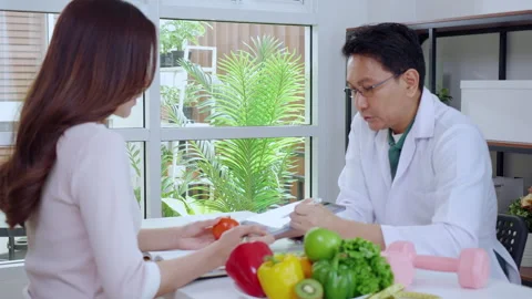 Asian nutritionist using tablet to explaining personalized meal plan with A.. Stock Footage 329913526