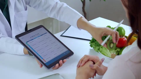 Asian nutritionist using tablet to explaining personalized meal plan with A.. Stock Footage 331269381