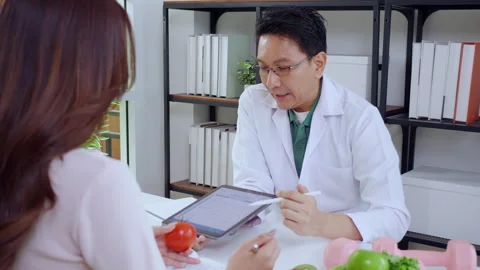 Asian nutritionist using tablet to explaining personalized meal plan with A.. Stock Footage 331269501