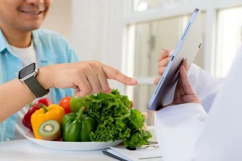 Asian nutritionist using tablet to explaining personalized meal plan with A.. Foto stock