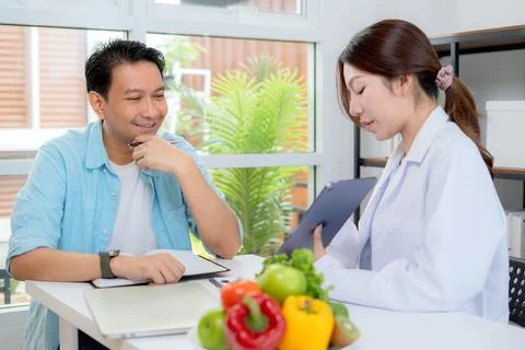 Asian nutritionist using tablet to explaining personalized meal plan with A.. Stock Photos